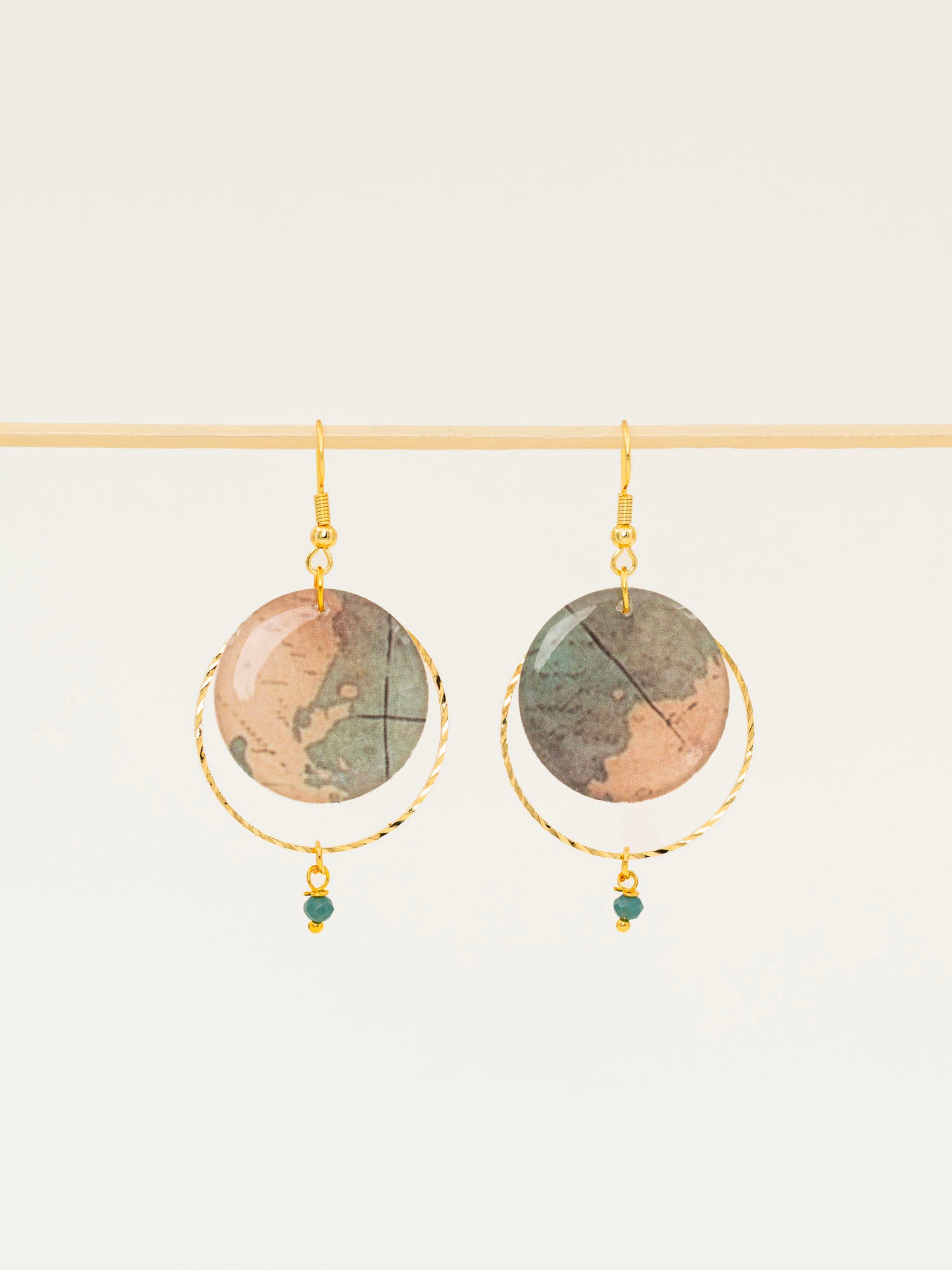 Boucles d'oreilles Sacramento, disque carte ancienne, anneau laiton doré torsadé et perle turquoise africaine, fond crème