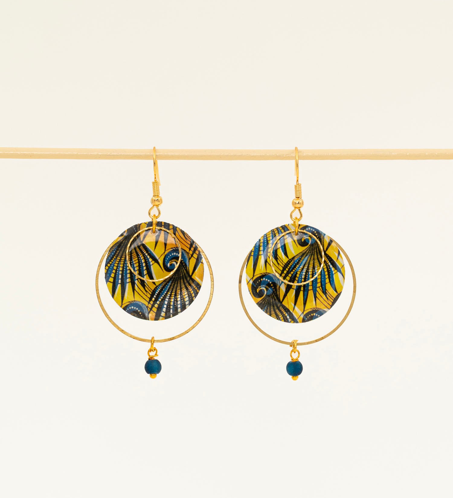 Boucles d'oreilles Conakry, disque wax jaune et bleu pétrole, anneau laiton brut et perle verre mat, fond crème