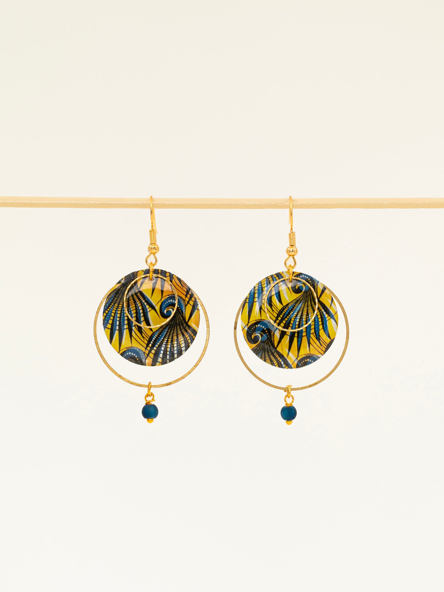 Boucles d'oreilles Conakry, disque wax jaune et bleu pétrole, anneau laiton brut et perle verre mat, fond crème