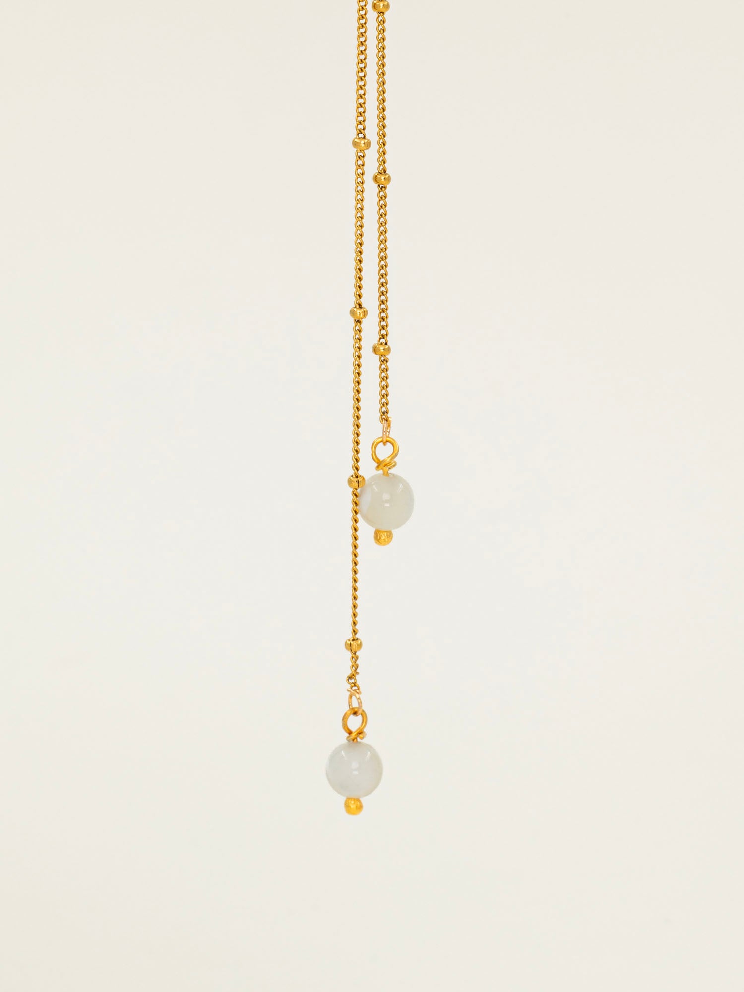 Collier Amalfi, chaîne satellite dorée forme Y et perles pierre de lune, fond crème