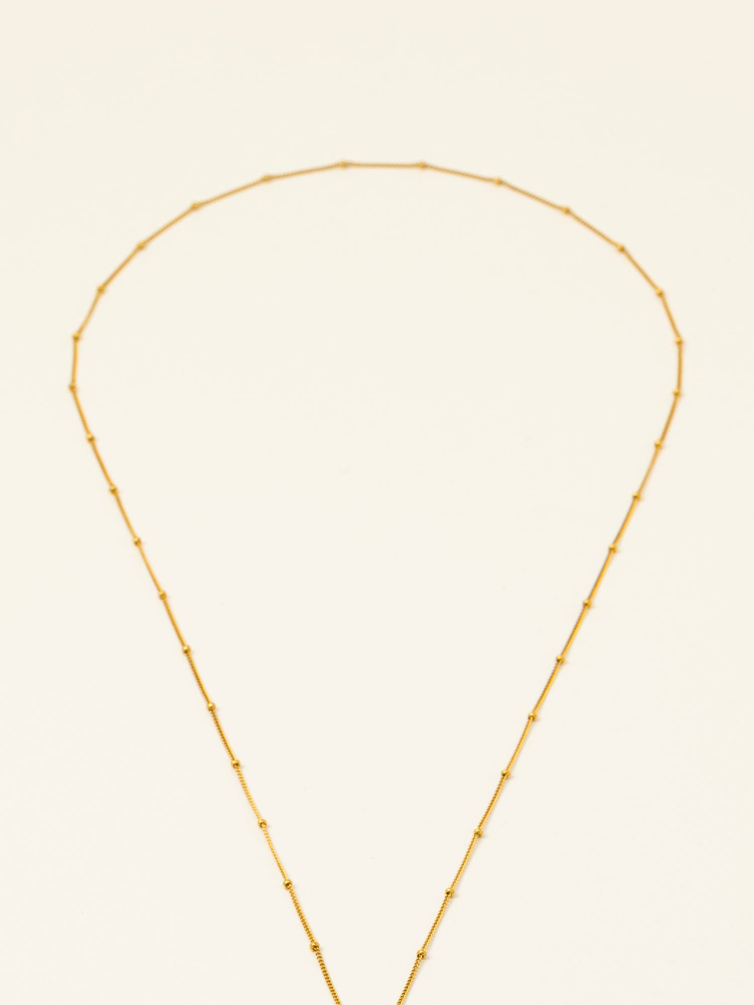 Collier Amalfi, chaîne satellite dorée forme Y et perles pierre de lune, fond crème