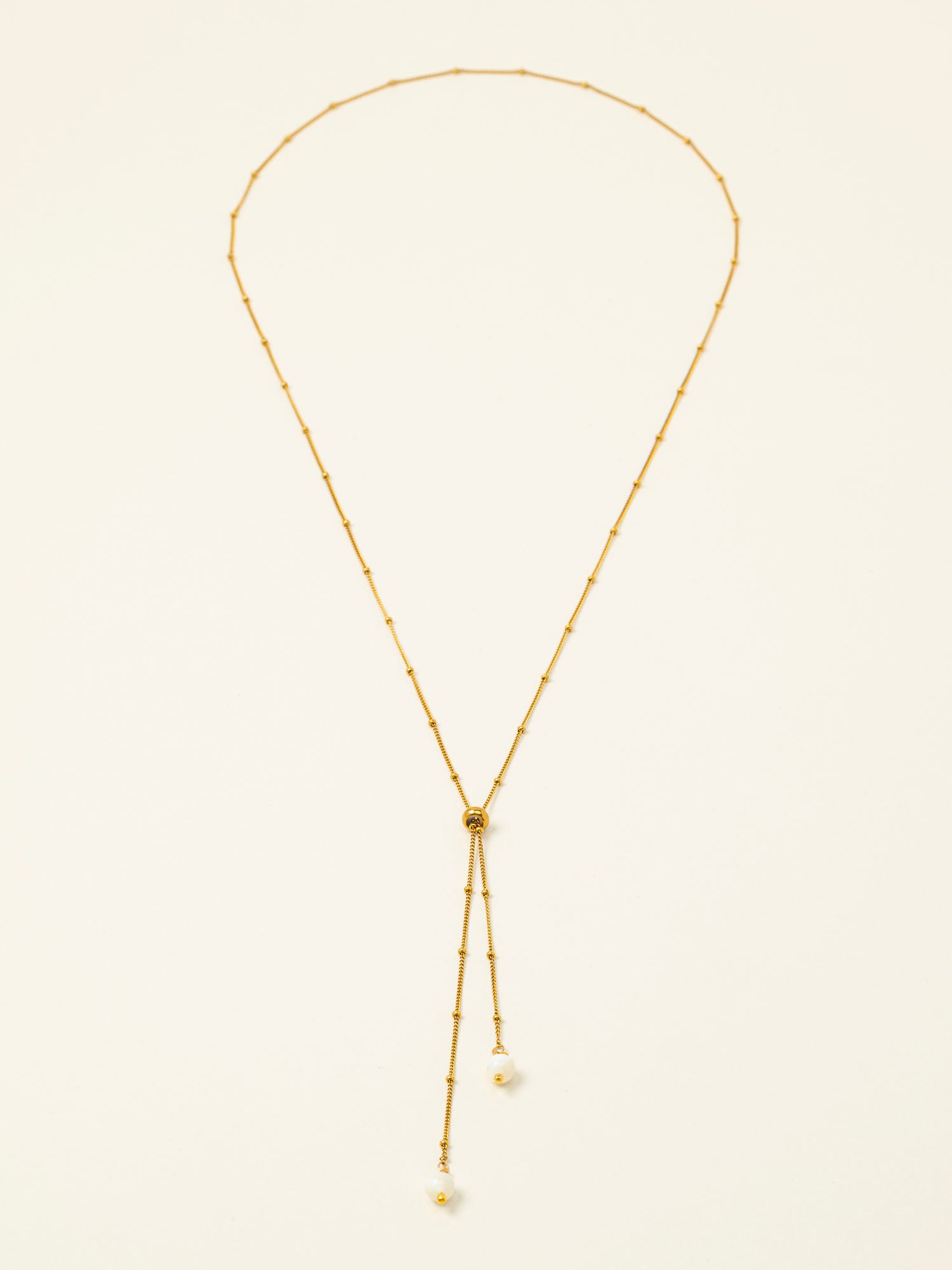 Collier Amalfi, chaîne satellite dorée forme Y et perles pierre de lune, fond crème