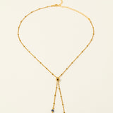 Collier Essaouira, chaîne satellite dorée forme Y et perles lapis-lazuli, fond crème