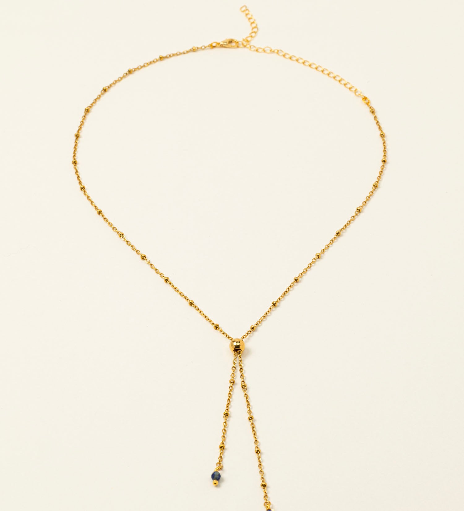 Collier Essaouira, chaîne satellite dorée forme Y et perles lapis-lazuli, fond crème
