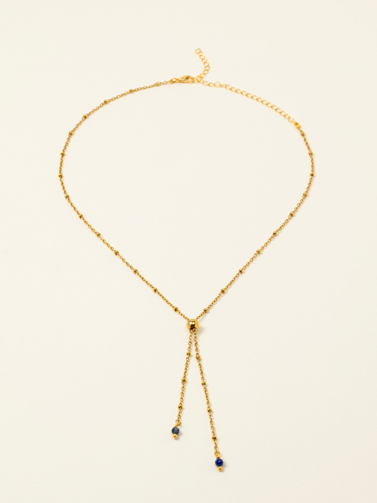 Collier Essaouira, chaîne satellite dorée forme Y et perles lapis-lazuli, fond crème