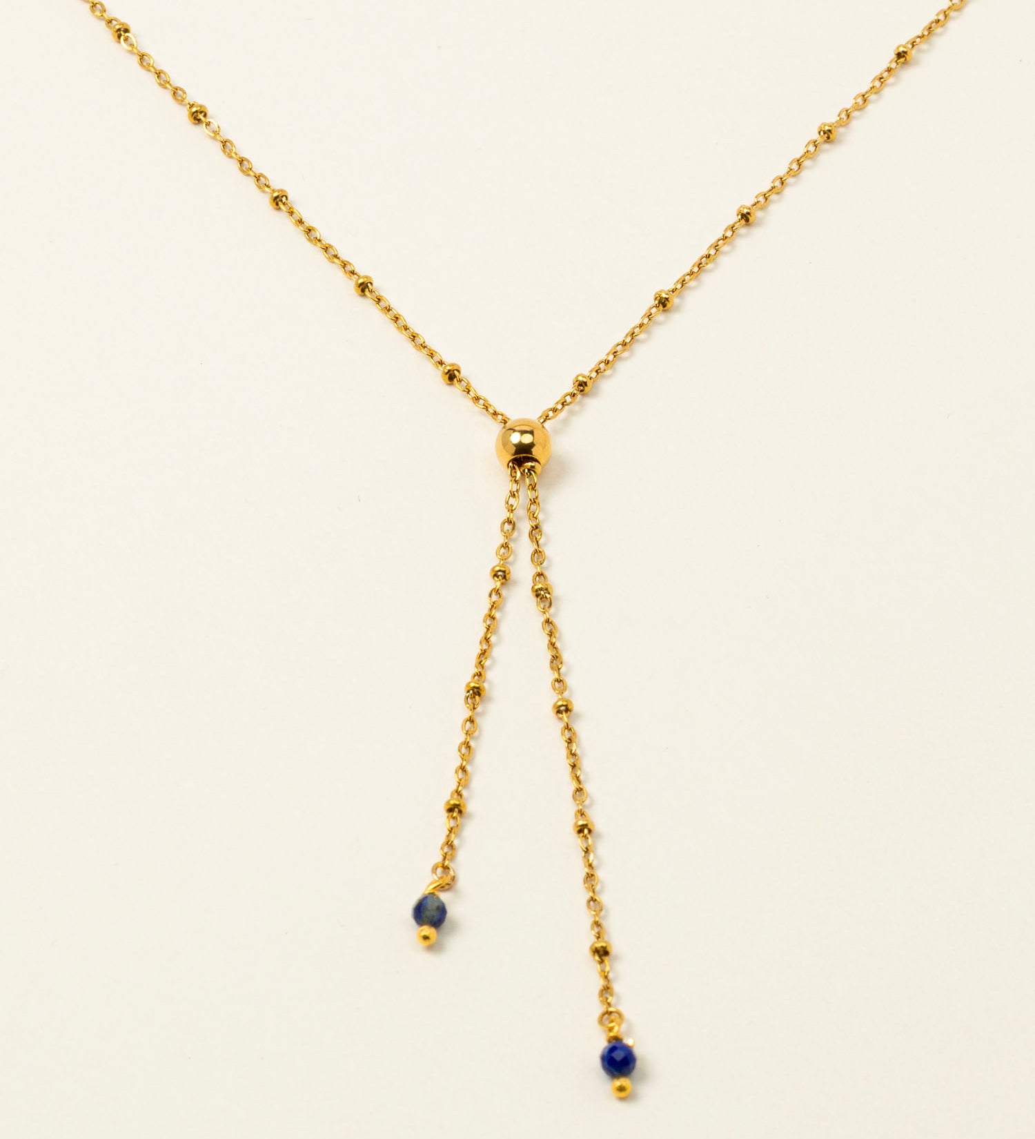 Collier Essaouira, chaîne satellite dorée forme Y et perles lapis-lazuli, fond crème