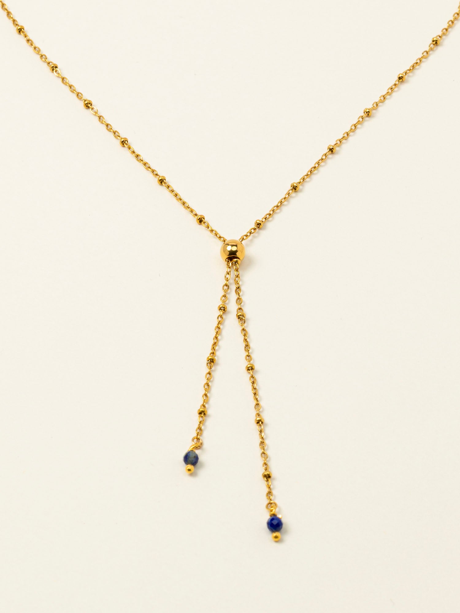 Collier Essaouira, chaîne satellite dorée forme Y et perles lapis-lazuli, fond crème