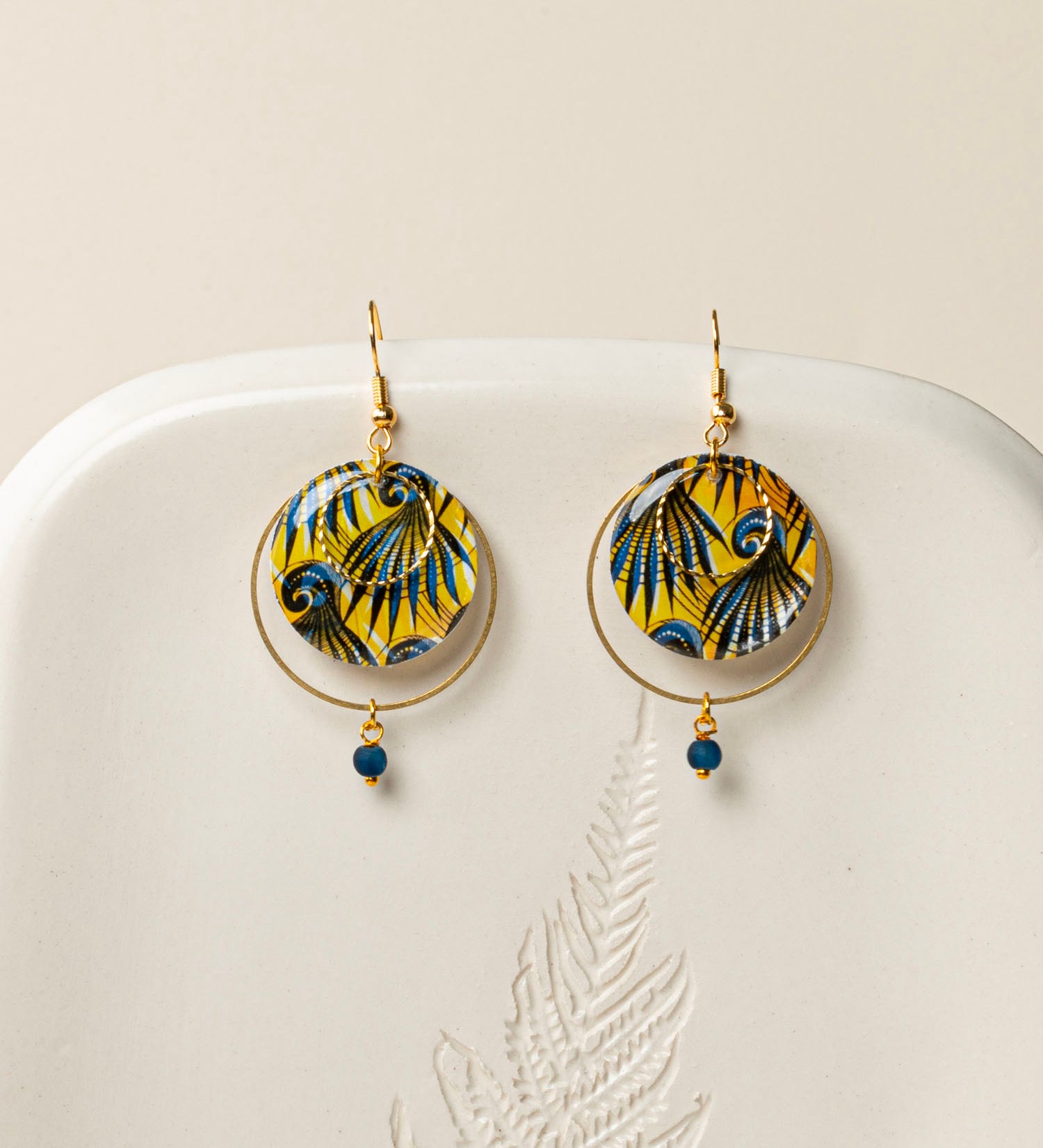 Boucles d'oreilles Conakry, disque wax jaune et bleu pétrole, anneau laiton brut et perle verre mat, fond crème