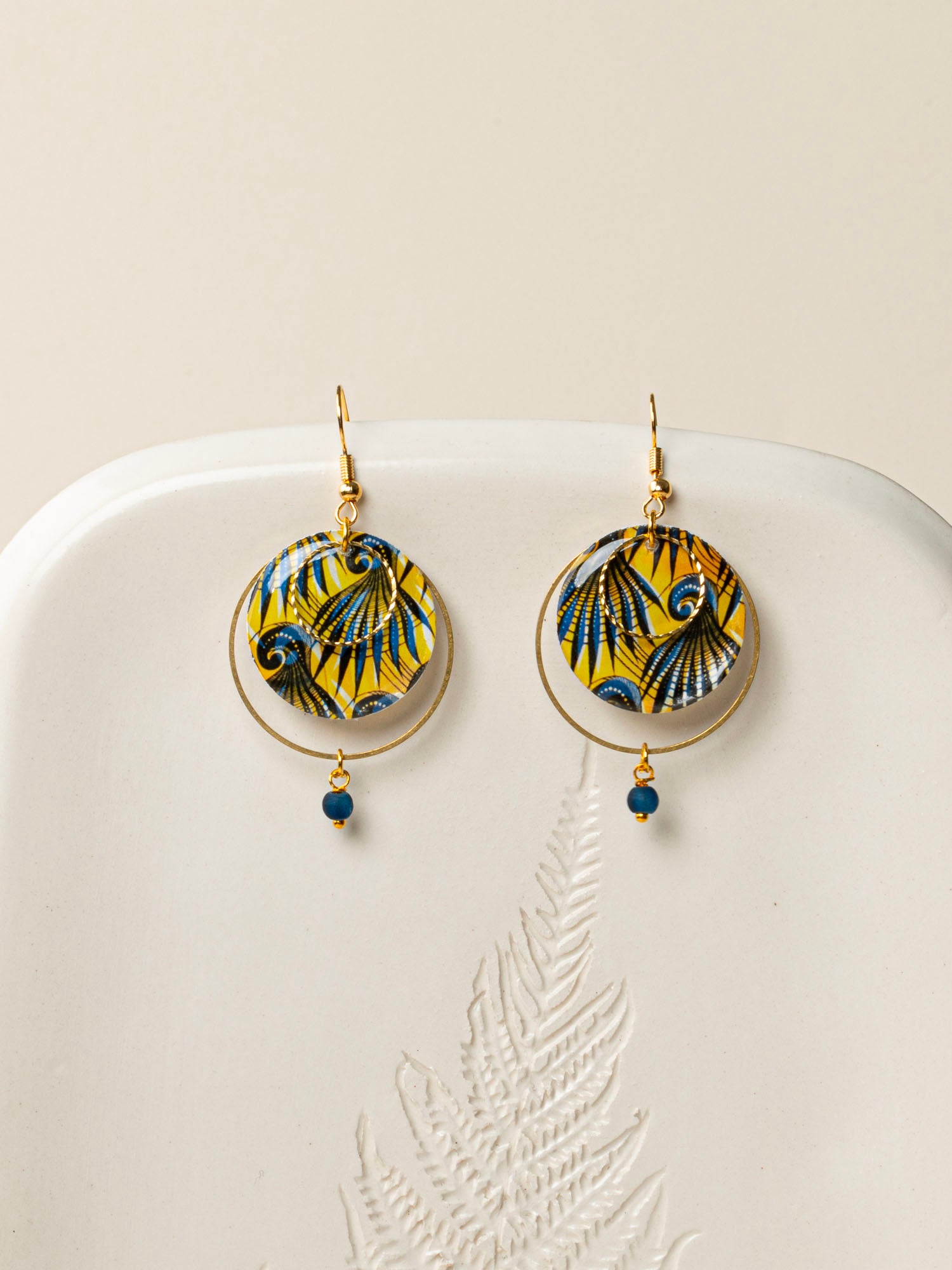 Boucles d'oreilles Conakry, disque wax jaune et bleu pétrole, anneau laiton brut et perle verre mat, fond crème