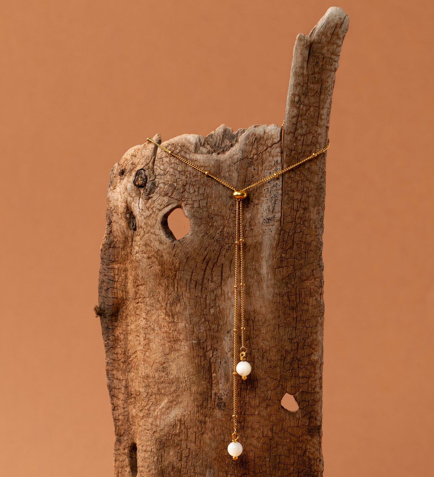 Collier Amalfi, chaîne satellite dorée forme Y et perles pierre de lune, fond crème